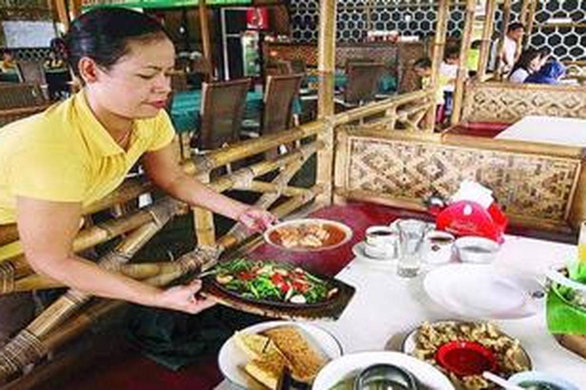 Pramusaji di Rumah Makan Sangkuriang di Jalan Sapta Pesona, Jatiasih, Bekasi, Jawa Barat, menghantarkan makanan pesanan pelanggan, Selasa (11/5/2010).