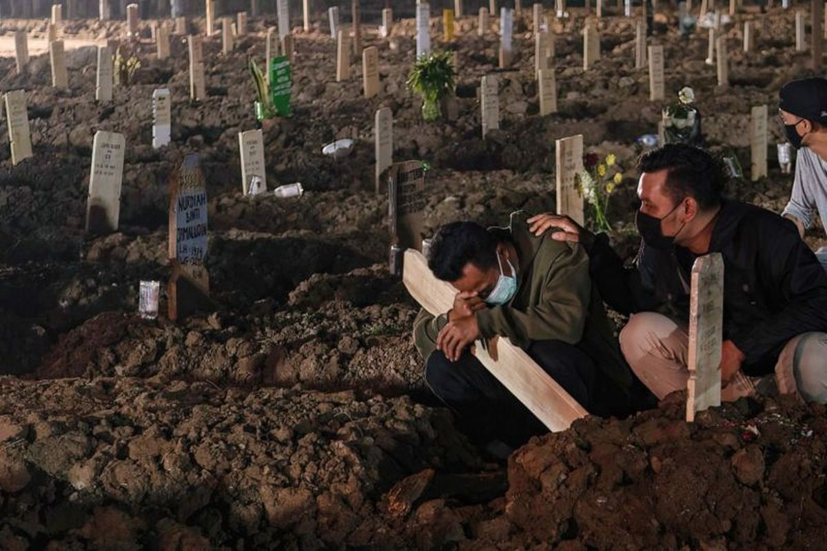 Seorang pria menangis di makam kerabatnya di lahan pemakaman penderita Covid-19 di TPU Rorotan Jakarta.