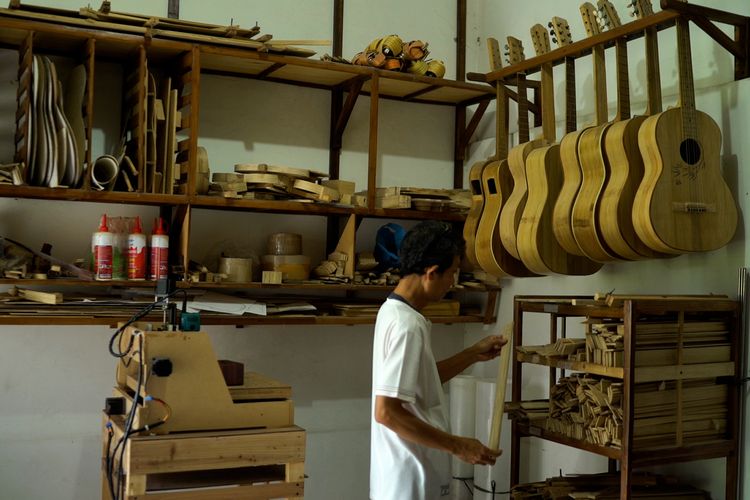 Seorang pekerja menyelesaikan pembuatan gitar akustik berbahan bambu di rumah produksi Lembaga Pendidikan Seni Nusantara (LPSN) di kawasan Bogor Barat, Bogor, Jawa Barat.
