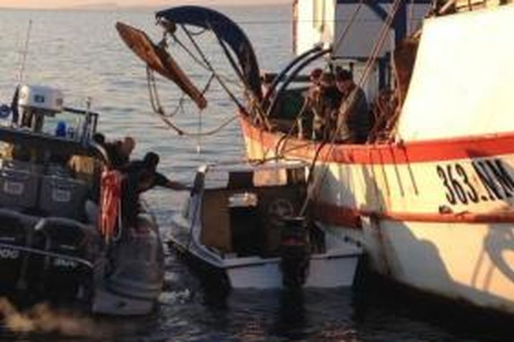 Dalam foto yang dirilis Pasukan Penjaga Pantai Yunani pada 18 Maret 2014 ini menampilkan aparat Yunani menarik sebuah kapal kecil yang digunakan para imigran gelap untuk mencapai Eropa. Peristiwa ini terjadi di lepas pantai pulau Lesvos, Yunani.