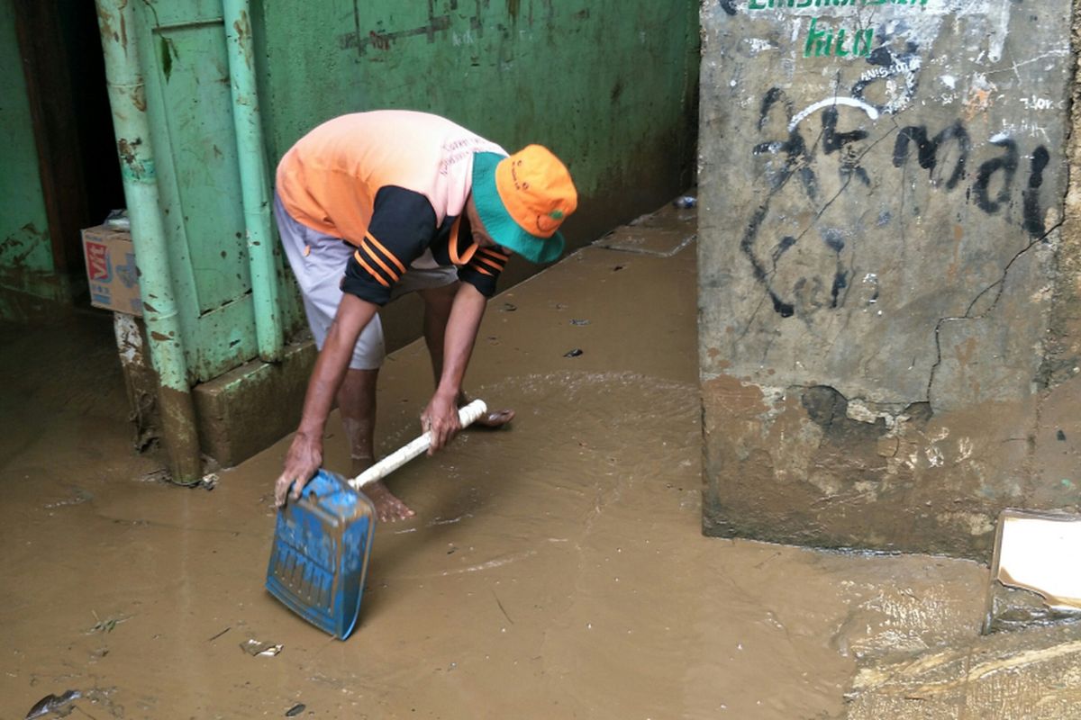 Petugas UPK Badan Air membersihkan lumpur di jalan permukiman menggunakan serokan sampah pasca-banjir luapangan Sungai Ciliwung di Kelurahan Rawajati, Jakarta Selatan, Selasa (6/2/2018).