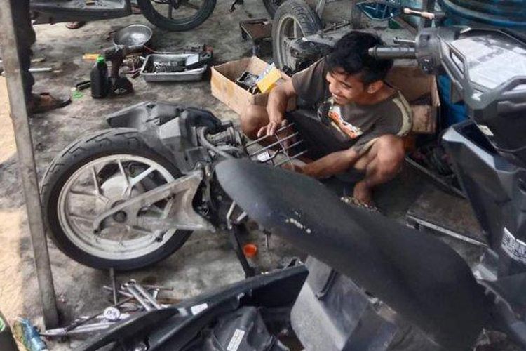 Karyawan bengkel di Sampang, Jawa Timur, menyervis sepeda motor pelanggan, Minggu (17/3/2024). Usai banjir Sampang surut, bengkel tersebut buka selama 14 jam karena kebanjiran pelanggan.