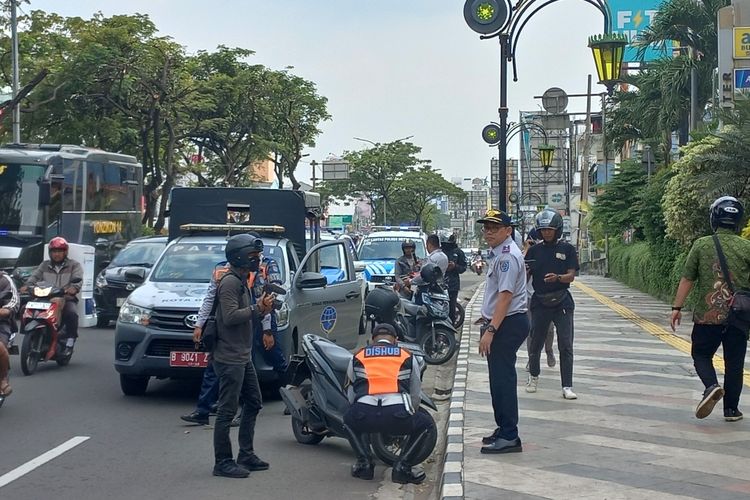 Dinas Perhubungan (Dishub) Kota Depok tengah mengempiskan ban motor yang terparkir di badan Jalan Raya Margonda, Depok, pada Selasa (14/3/2023).