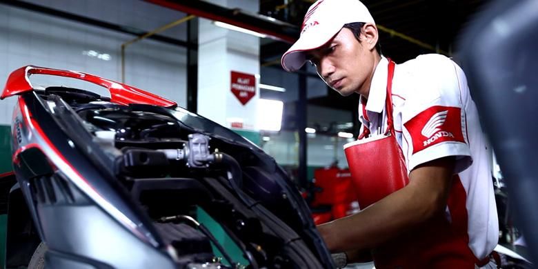 Teknisi perawatan motor sedang bekerja di bengkel