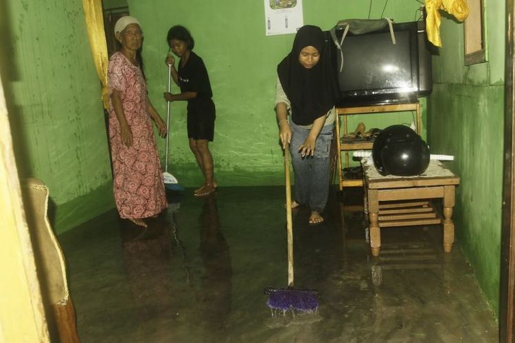 Warga mengeringkan ruangan yang terendam oleh air laut saat terjadi banjir ROB di pesisir pantai Kampung Nelayan Oesapa, Selasa (12/3). 