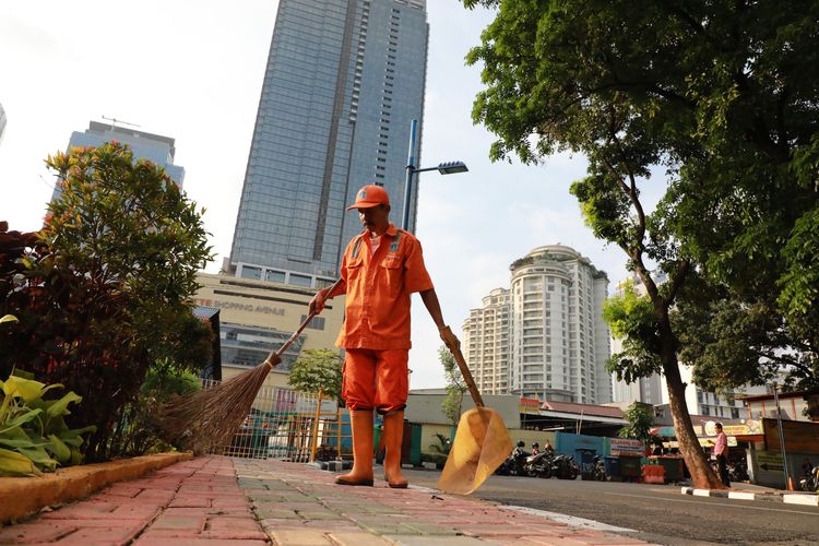 Petugas kebersihan sedang membersihkan taman yang ada di Jakarta.