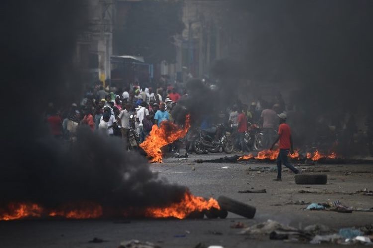 Ban dibakar oleh para demonstran pada hari keempat protes di Port-au-Prince, Haiti, Minggu (10/2/2019), yang mendesak Presiden Haiti Jovenel Moise mundur. (AFP/RETAMAL HECTOR)