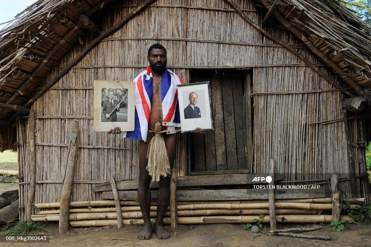 Sikor Natuan, putra kepala suku terpencil Yaohnanen di Tanna di Vanuatu, memegang dua potret Pangeran Philip dari Inggris di depan gubuk pada 6 Agustus 2010. Suku tersebut memuja Pangeran Philip sebagai dewa.