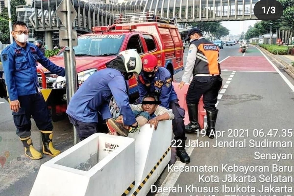 Seorang pria yang diduga Orang Dengan Gangguan Jiwa (ODGJ) terjebak di dalam rongga pembatas jalan sepeda permanen di Jalan Sudirman, Jakarta Pusat, Senin (19/4/2021). Petugas pemadam kebakaran pun dikerahkan untuk mengevakuasi pria berusia 60 tahun itu. 