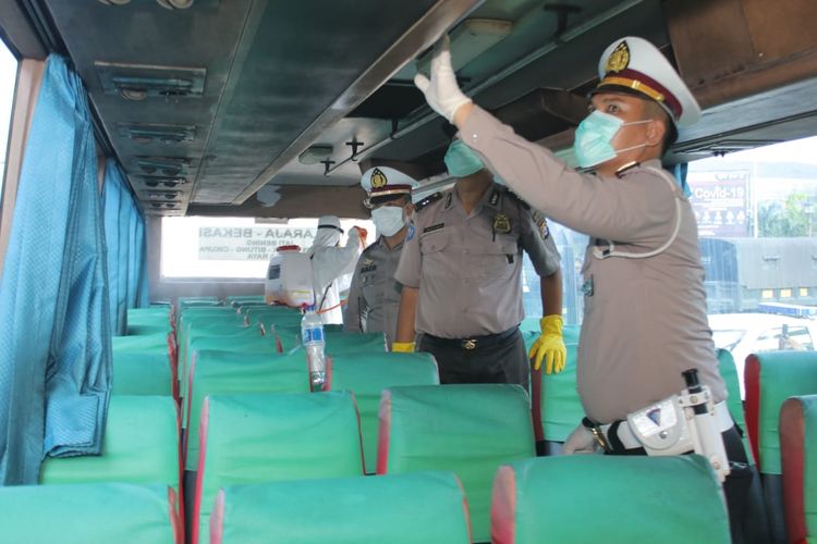 Anggota Polresta Tangerang melakukan penyemprotan disinfektan di kendaraan umum keluar Tol Tangerang-Merak, Minggu (22/3/2020)