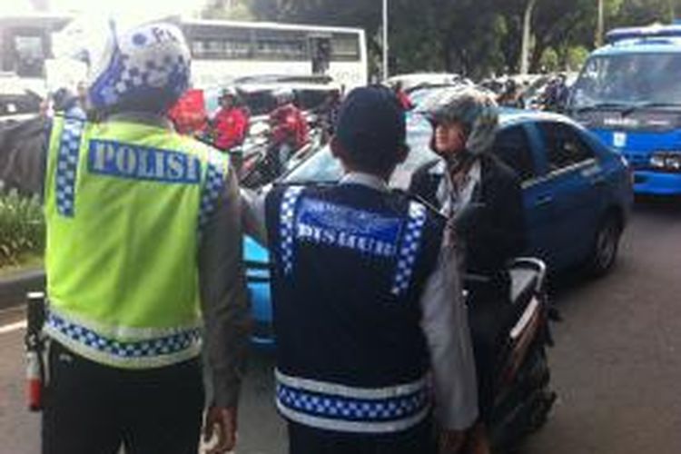 Pengendara motor bertanya kepada petugas jalan menuju tujuannya di hari pertama uji coba pembatasan sepeda motor di Jalan MH Thamrin hingga Jalan Medan Merdeka Barat, Rabu (17/12/2014).