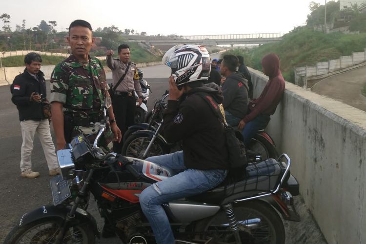 Babinsa dan Bhabinkamtibmas Pamulihan memberikan arahan kepada sejumlah pemuda yang kedapatan melakukan aksi balapan liar di lokasi Tol Cisumdawu, Sumedang, Jawa Barat, Selasa (7/5/2019). AAM AMINULLAH/KOMPAS.com