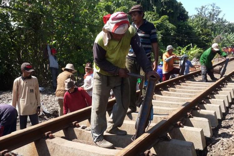 Sejumlah petugas saat memperbaiki rel kereta yang jebol karena diterjang banjir di Dusun Botokan, Desa Tambakrejo, Kecamatan Kraton, Kabupaten Pasuruan, Jumat (1/7/2016)