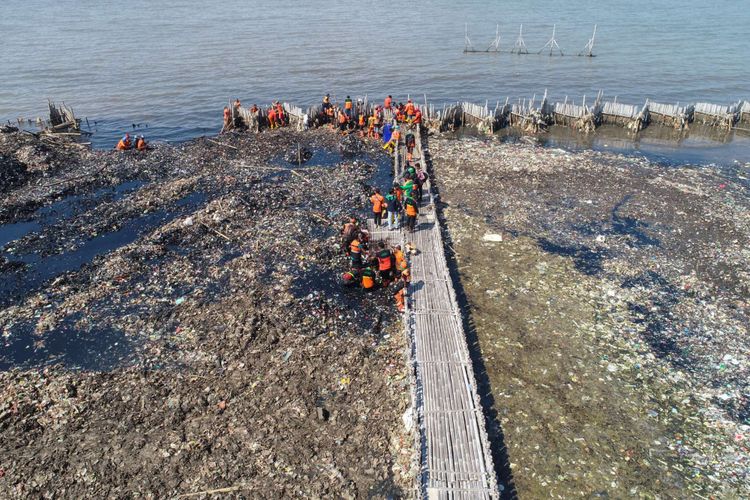 Petugas membersihkan lautan sampah yang menumpuk di kawasan Teluk Jakarta, Muara Angke, Jakarta Utara, Minggu (18/3/2018). Pencemaran limbah domestik rumah tangga di Teluk Jakarta ini memenuhi perairan seluas 7.500 meter persegi.