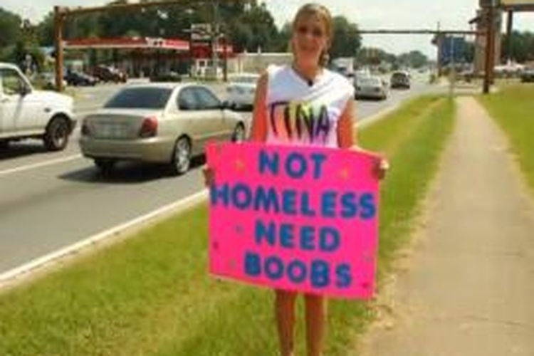 Christina Andrews, membawa spanduk berwarna merah muda dengan tulisan biru terang untuk menarik perhatian para pengguna jalan di Pensacola, Florida, AS.