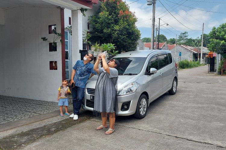 Keluarga Rian melihat gerhana matahari dengan mengenakan kacamata