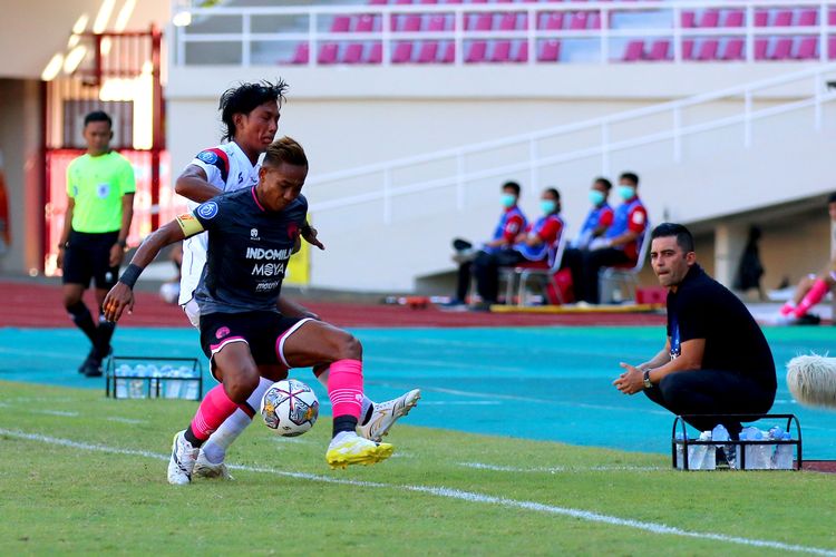 Pemain Persita Tangerang Muhammad Toha berebut bola dengan pemain Arema FC Johan Ahmad Farizi yang disaksikan pelatih Javier Roca saat pertandingan pekan ke-15 Liga 1 2022-2023 yang berakhir dengan skor 2-0 di Stadion Manahan Solo, Sabtu (17/12/2022) sore.