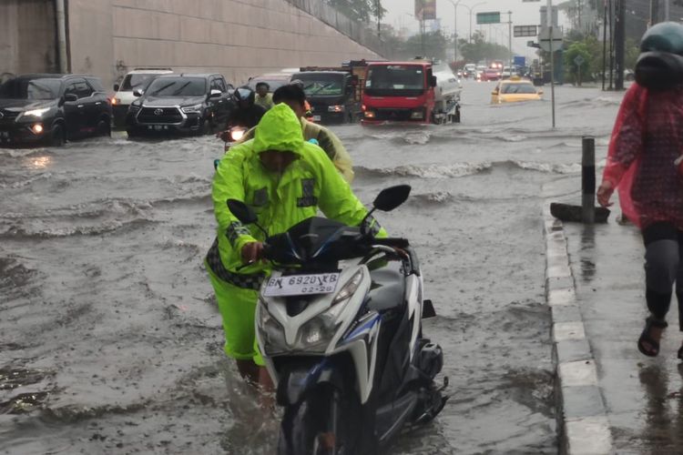 Petugas kepolisian membantu mendorong kendaraan warga yang mogok akibat menerobos banjir di Kota Pekanbaru, Riau, Rabu (6/9/2023).