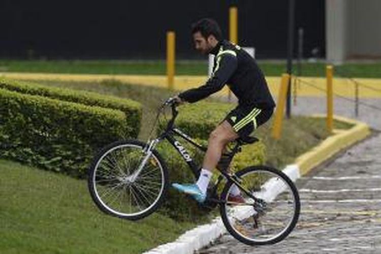 Gelandang Cesc Fabregas mengendarai sepeda ke pusat latihan tim nasional Spanyol, di CT do Caju, Curitiba, Minggu (15/6/2014).