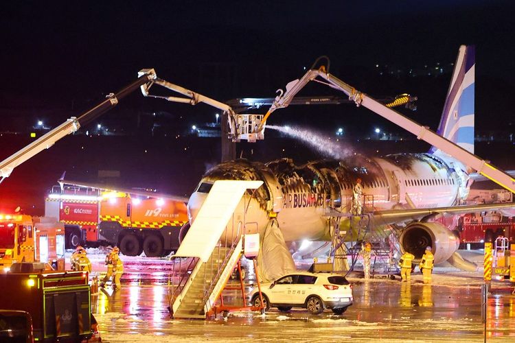 Petugas pemadam kebakaran berusaha memadamkan api yang membakar pesawat penumpang Air Busan di Bandara Internasional Gimhae, Busan, Korea Selatan, pada Selasa (28/1/2025).