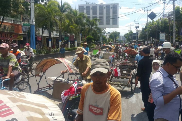 Ratusan tukang becak pulang setelah mendapatkan bantuan sembako dari Presiden Jokowi di Alun-Alun Kota Madiun, Kamis (29/3/2018) siang.