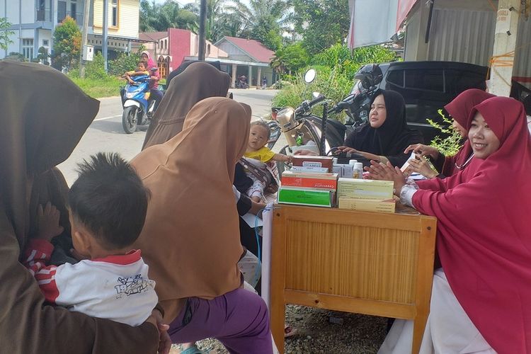 Warga membawa anak-anaknya berobat ke posko kesehatan akibat terserang penyakit di Desa Padang Luas, Kecamatan Tambang, Kabupaten Kampar, Riau, Selasa (17/12/2019).