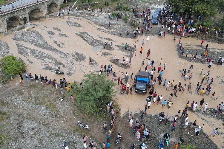 Foto udara pengendara melintasi sungai akibat jembatan amblas dan tidak dapat dilalui di Kelurahan Buluri di Palu, Sulawesi Tengah, Jumat (7/4/2023). Jembatan pada jalur penghubung Kota Palu dan Donggala hingga ke Sulawesi Barat dan Sulawesi Selatan serta menjadi salah satu jalur utama bagi pemudik tersebut terputus sehingga pengguna jalan terpaksa melintasi sungai.