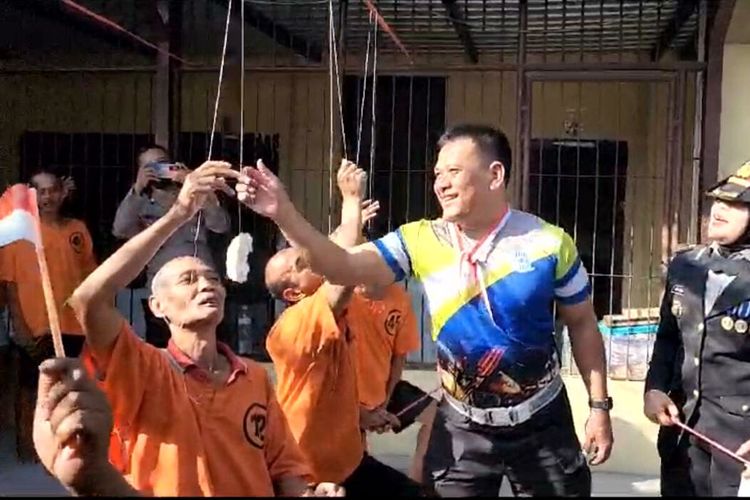 Seorang polisi membetulkan benang yang melilit jari seorang tahanan peserta lomba makan kerupuk di ruang tahanan Polres Blitar Kota, Kamis (17/8/2023)