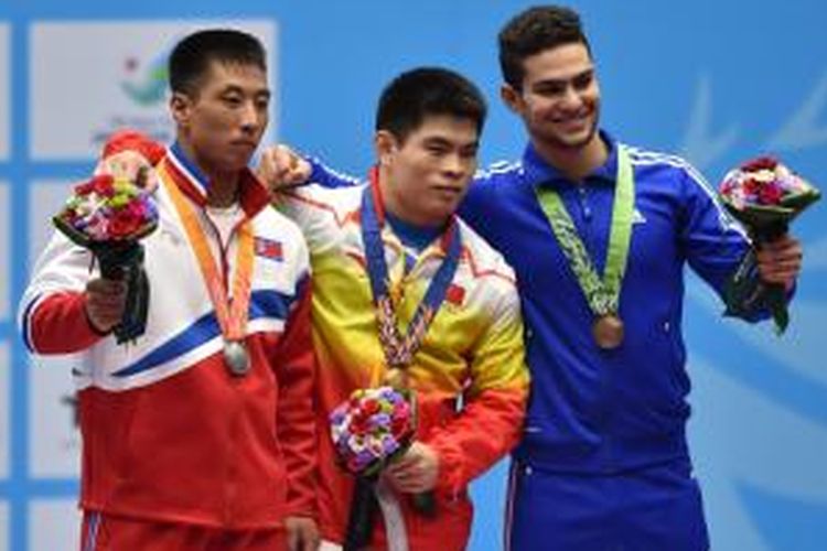 Atlet angkat besi Tiongkok, Lin Qingfen (tengah), berpose bersama atlet Korea Utara, Kim Myong Hyok (kiri) dan atlet Irak, Mohammed Kadhum, setelah menyelesaikan nomor 69 kg angkat besi Asian Games 2014 di Incheon, Korea Selatan, Senin (22/9/2014).