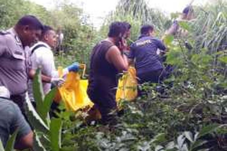 Sejumlah petugas kepolisian tengah mengangkat kantong mayat remaja putri yang di temukan warga Kendari di semak-semak pinggir sungai