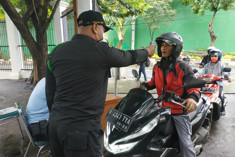 Petugas DPR mengecek suhu tubuh pengunjung dengan alat thermal gun di pintu masuk Kompleks Parlemen, Jakarta, Kamis (5/3/2020).