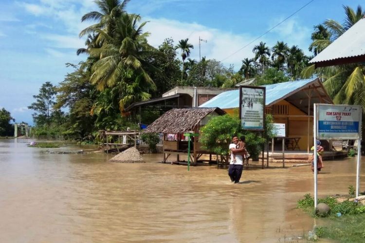 Warga melintas di lokasi banjir Desa Parang Sikureung, Kecamatan Matangkuli, Kabupaten Aceh Utara, Kamis (17/5/2018).