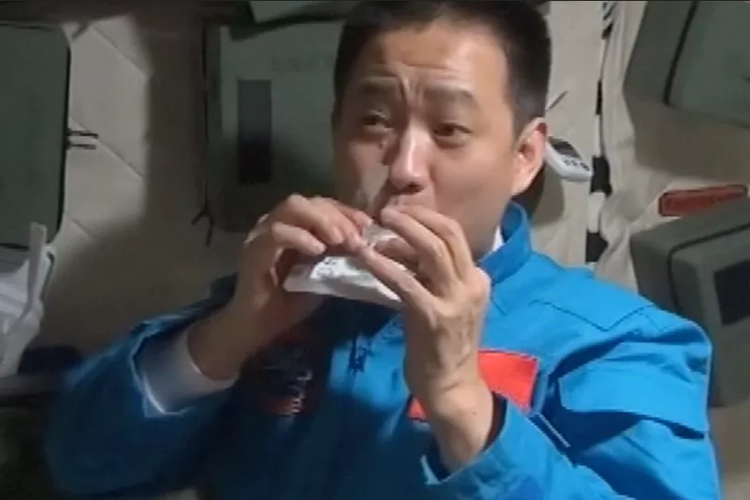 Salah satu astronot sedang menunjukkan paket menu makanan yang dikonsumsinya. Selama tiga bulan tinggal di stasiun luar angkasa Tianhe, ketiga astronot China dibekali 120 menu makanan. 