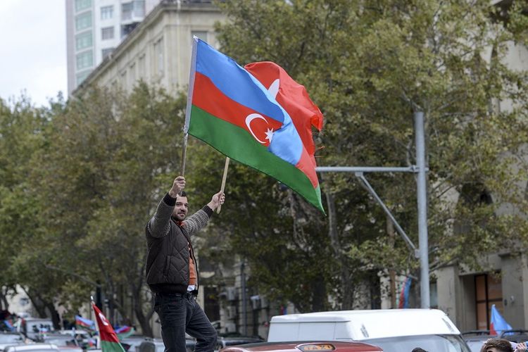 Seorang pria Azerbaijan mengibarkan bendera Azerbaijan dan bendera Turki setelah Presiden Azerbaijan Ilham Aliyev mengklaim pasukan Azerbaijan telah merebut Shushi, sebuah kota utama di wilayah Nagorno-Karabakh yang telah di bawah kendali etnis Armenia selama beberapa dekade di Baku, Azerbaijan, Minggu (8/11/2020).