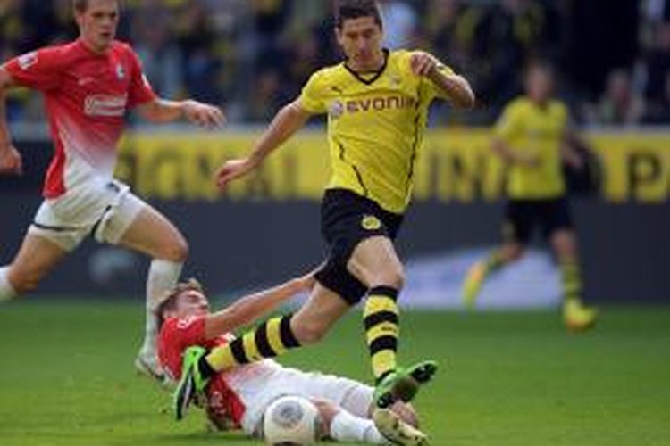 Penyerang Borussia Dortmund Robert Lewandowski (kanan) melewati adangan bek Freiburg  Matthias Ginter, pada pertandingan Bundesliga, di Signal Iduna Park, Sabtu (28/9/2013).