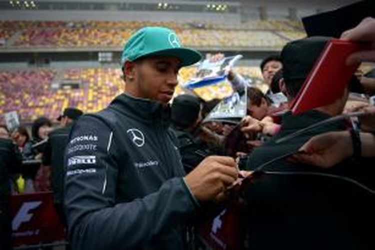 Pebalap Mercedes asal Inggris, Lewis Hamilton, memberikan tanda tangan pada para penggemar jelang GP China di Sirkuit Internasional Shanghai, Kamis (18/4/2014).