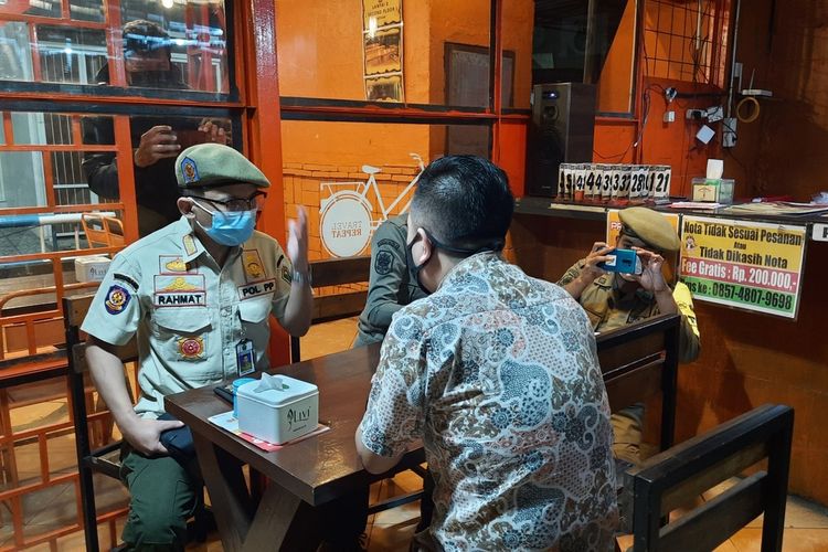 Petugas Satpol PP Kota Malang saat memperingati pemilik rumah makan di Jalan Sigura-gura Kota Malang karena melanggar jam operasional PPKM pada 15 Januari 2021 malam.