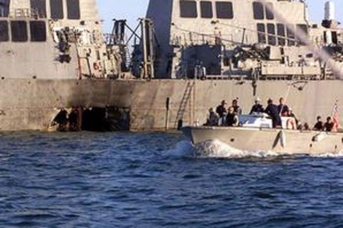 Pasukan Marinir AS berpatroli di dekat USS Cole yang lambungnya berlubang akibat dibom kelompok militan saat bersandar di pelabuhan Aden Yaman, Oktober 2000. Pemerintah Yaman telah mengusir 16.000 anggota Al Qaeda dari negeri itu.