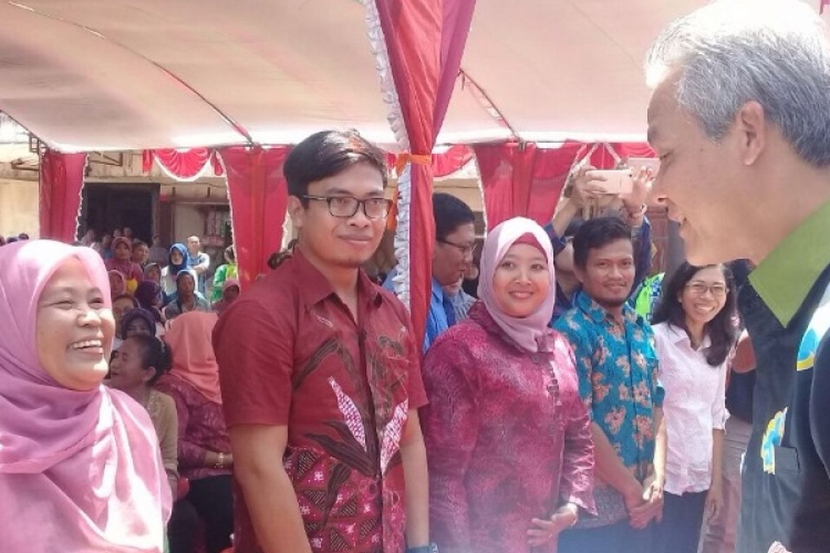 Gubernur Jawa Tengah Ganjar Pranowo menyerahkan surat keterangan pengajuan kredit pada Suyanto (tengah) di sela kegiatan di Pasar Godong, Grobogan, Rabu (8/3/2017).