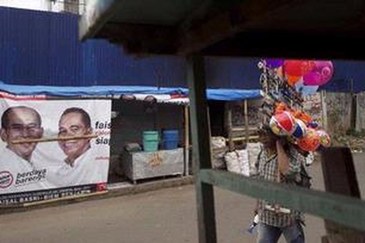 Penjual balon keliling melintas di depan baliho bergambar calon independen Gubernur DKI 2012-2017 Faisal Basri - Biem Benjamin di Menteng Atas, Jakarta Selatan, Kamis (29/12/2011). Baliho bergambar calon gubernur DKI 2012-2017 mulai bertebaran di sudut kota Jakarta.