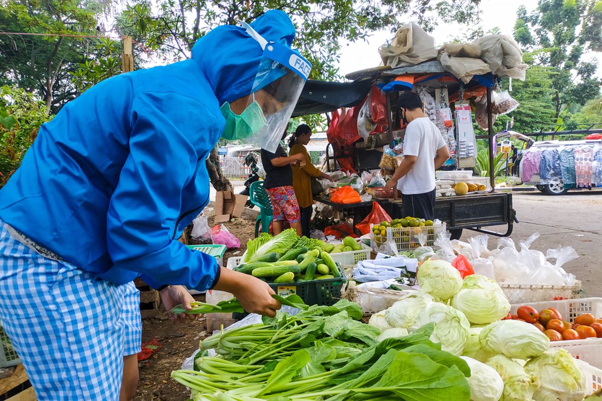 Pedagang sayuran dengan masker dan pelindung wajah. 