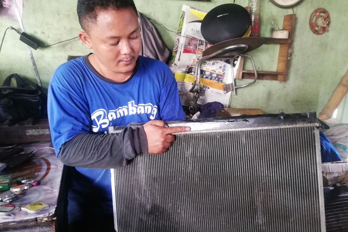 Teknisi bengkel spesialis radiator menunjukkan salah satu contoh radiator 