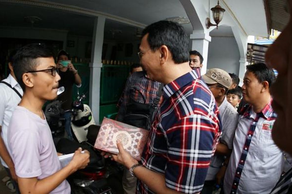 Seorang pemuda yang mengikuti aksi damai memberi sebuah Al-Quran kepada calon gubernur DKI Jakarta Basuki Tjahaja Purnama saat blusukan ke kawasan Ulujami, Pesanggrahan, Jakarta Selatan, Kamis (26/1/2017).