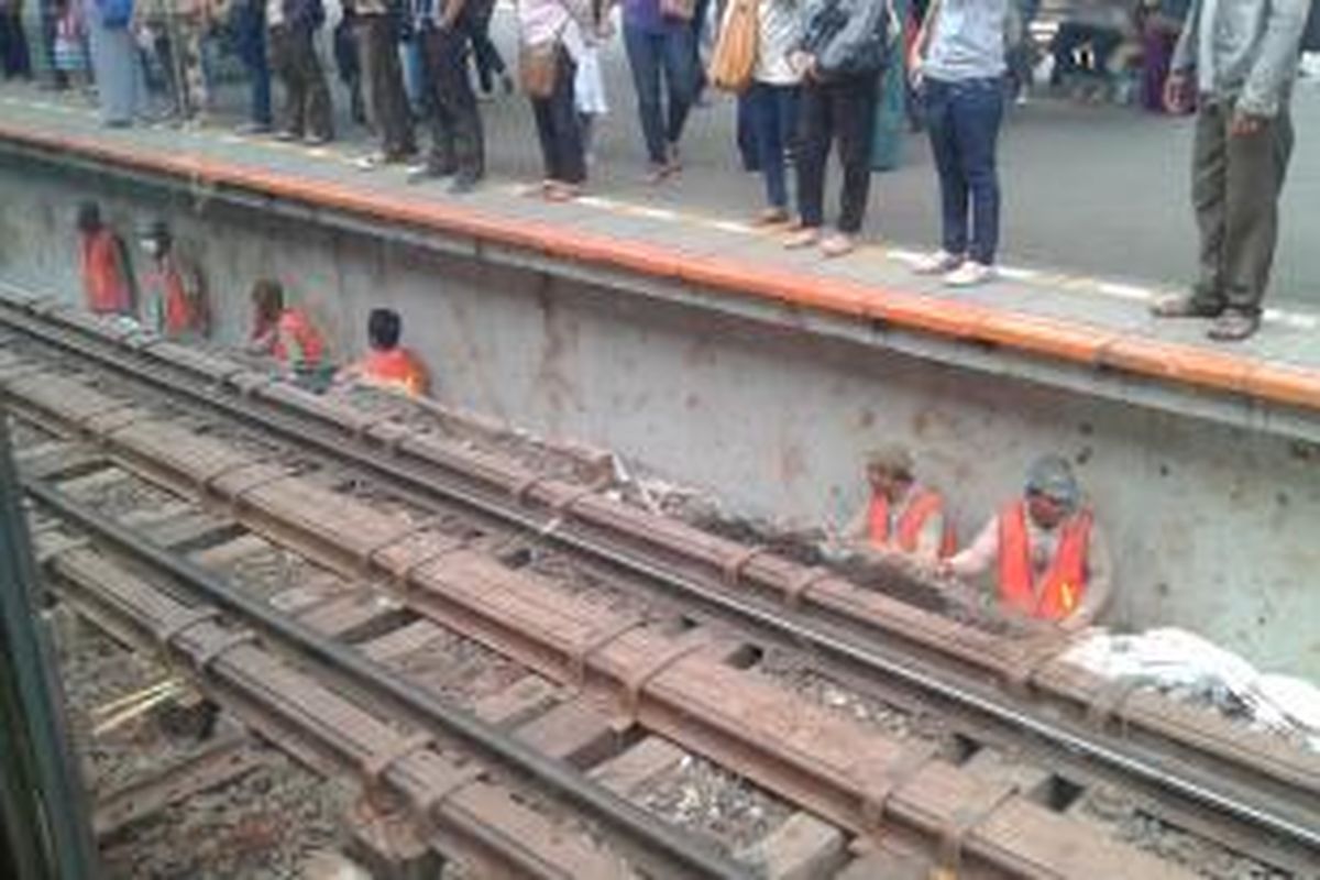 Para tukang yang bekerja membangun terowongan di bawah rel Stasiun Manggarai tengah menunggu kereta yang lewat sambil merapatkan diri ke dinding peron, Rabu (4/2/2015).
