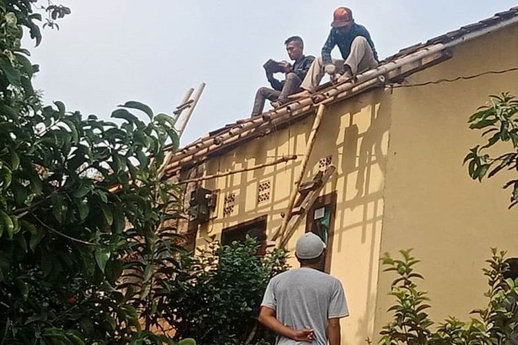 Sejumlah warga Cianjur, Jawa Barat tengah membetulkan genteng rumah akibat diterjang angin puting beliung dan hujan deras, Minggu (27/10/2019)