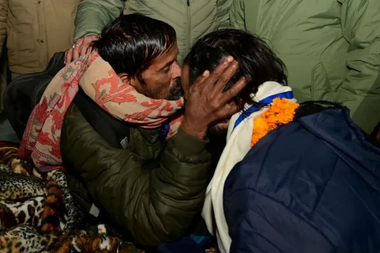 Seorang pria mencium kerabatnya, yang baru dibebaskan, pada Selasa (28/11/2023), setelah terperangkap di terowongan selama dua pekan.