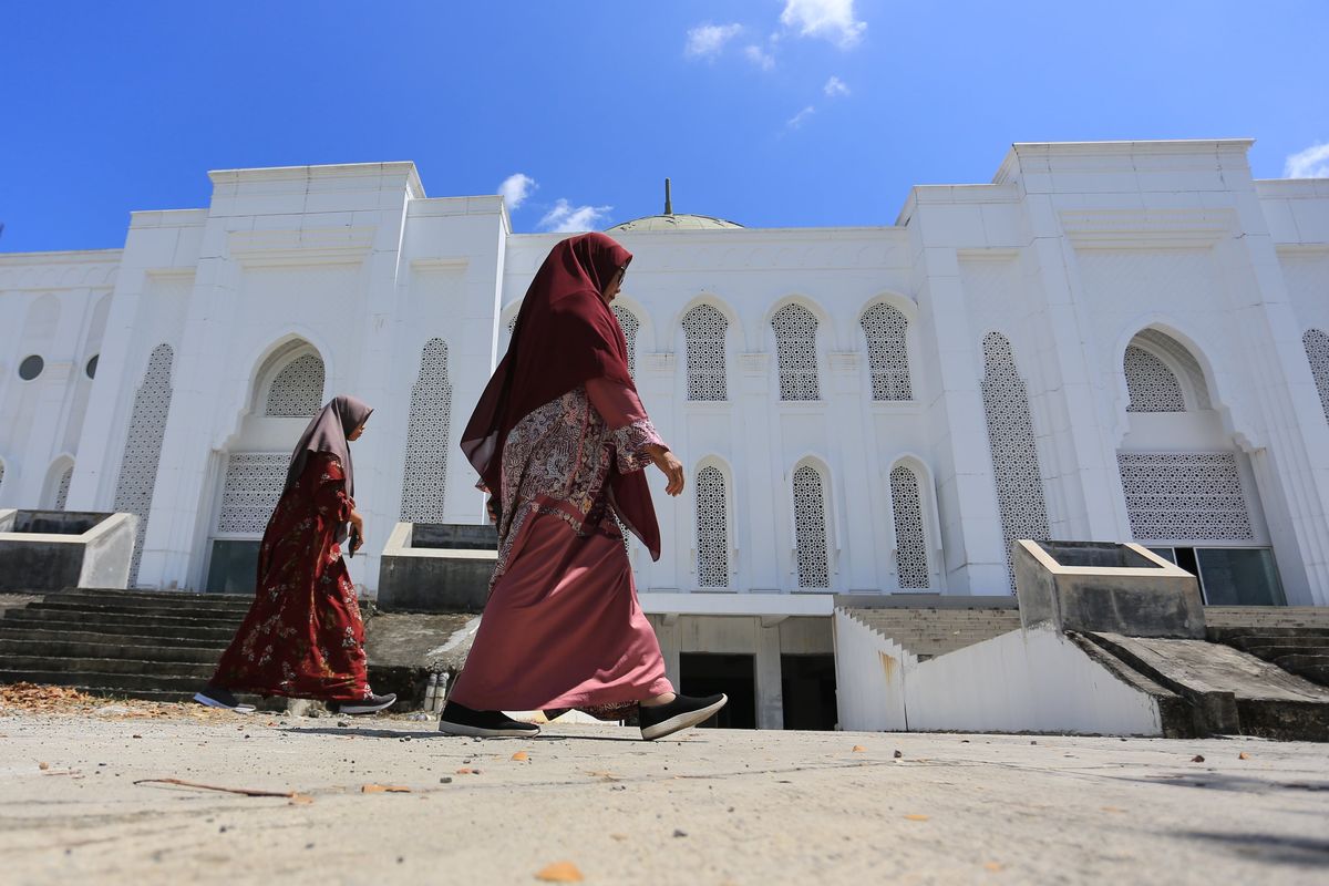 Sejumlah pengunjung berjalan di halaman Masjid Giok atau Masjid Agung Baitul A'la Desa Lueng Baro, Suka Makmur, Nagan Raya, Aceh, Minggu (10/4/2022). Masjid Agung Baitul A'la Nagan Raya yang dibangun sejak tahun 2012 tersebut dirancang menggunakan perpaduan arsitektur khas Asia Tenggara, Timur Tengah dan Aceh dengan ornamen berlapis batu giok pada lantai, dinding, tiang dan kubah masjid yang proses pembangunannya memasuki tahap penyelesaian atau sekitar 80 persen sehingga akan dibuka untuk umum pada Juni 2022 mendatang. ANTARA FOTO/Syifa Yulinnas/nym.