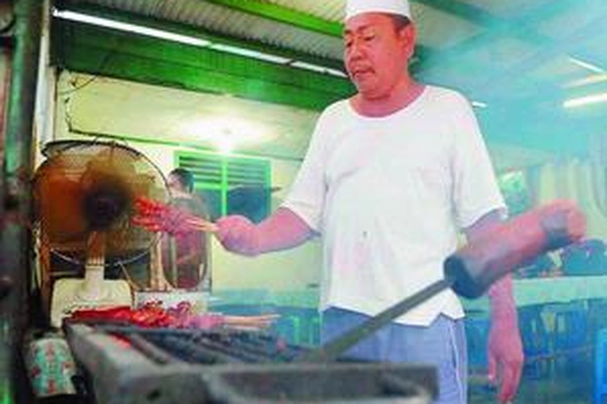 Haji Suaip membakar sate kambing di warungnya di kawasan Kemandoran, Jakarta Selatan, Jumat (26/9). 