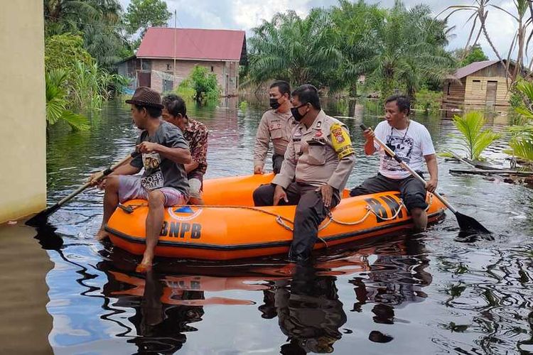 Anggota Polres Dumai membawa seorang warga lansia yang membutuhkan bantuan makanan dan obat, karena masih bertahan di rumahnya yang dilanda banjir di Kelurahan Bukit Datuk, Kecamatan Dumai Selatan, Kota Dumai, Riau, Sabtu (30/10/2021).