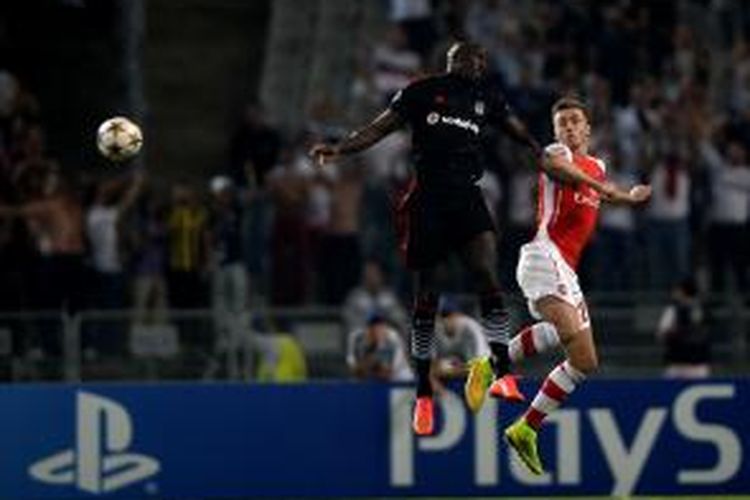 Bomber Besiktas, Demba Ba, berebut bola dengan bek Arsenal, Calum Chambers, pada pertandingan leg pertama play-off Liga Champions, Selasa atau Rabu (20/8/2014) dini hari WIB. 